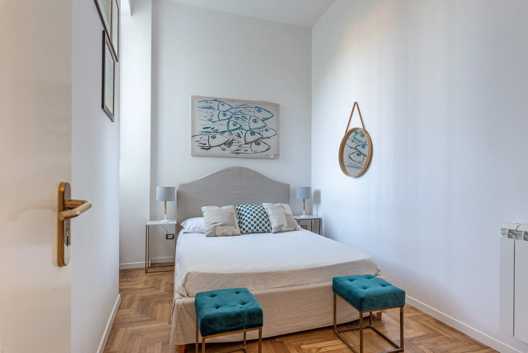 A bright bedroom with a bed, two bedside tables, and upholstered seating.