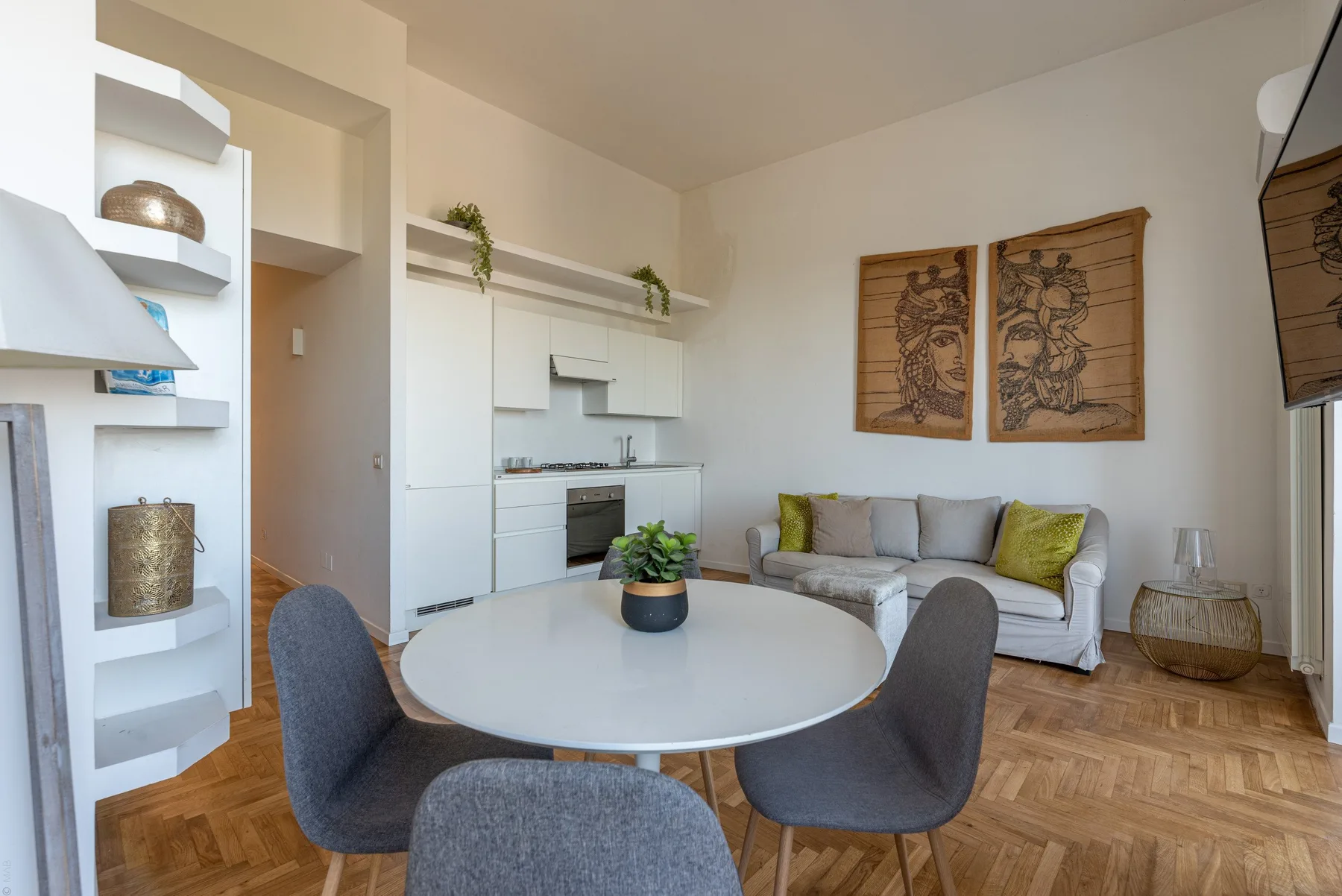 A bright living area with a compact kitchen, round table, and seating.