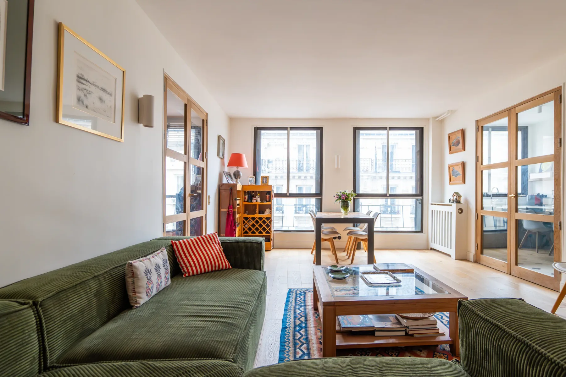 Una sala luminosa con asientos, una mesa de centro y ventanas grandes.