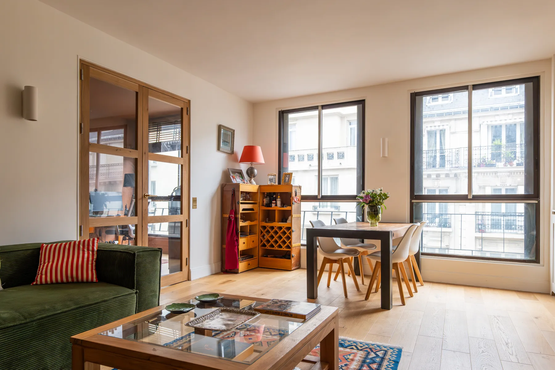 Una luminosa sala de estar y comedor con grandes ventanas y una mesa.