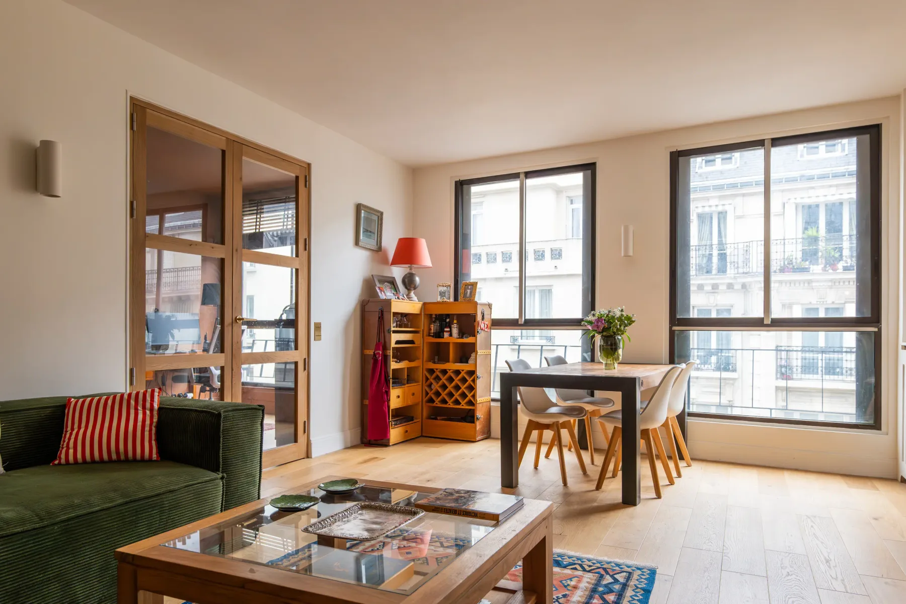 Una luminosa sala de estar y comedor con grandes ventanas y asientos.