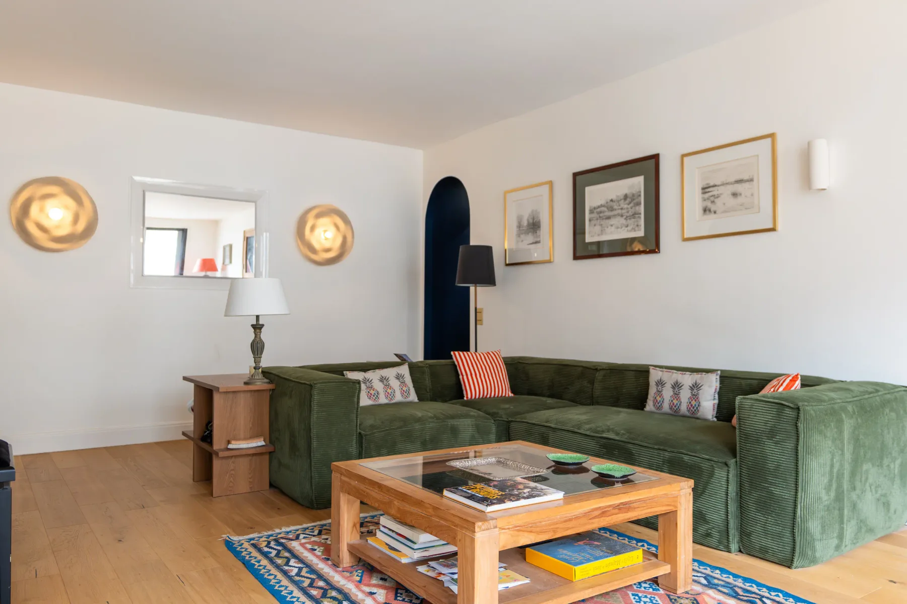 Una sala de estar luminosa con asientos verdes y una mesa de centro de madera.