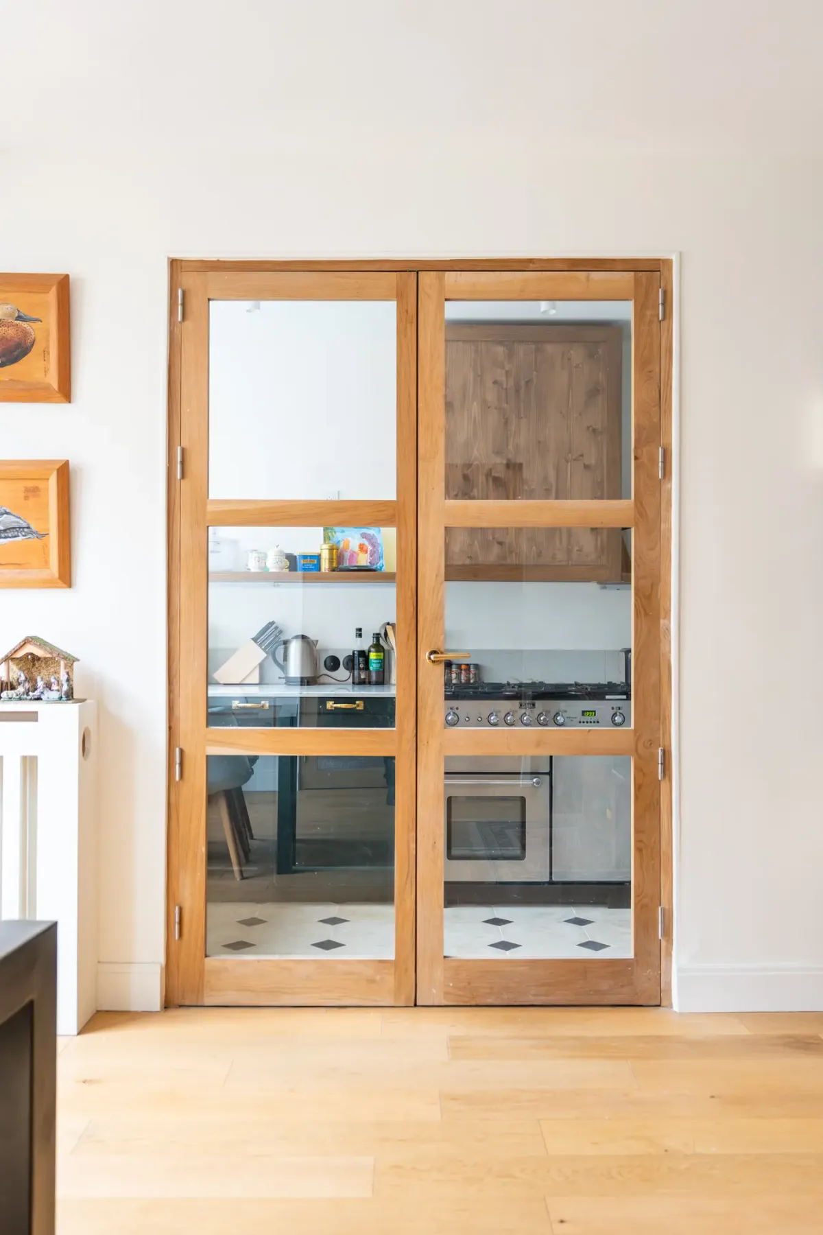 Se ve una cocina a través de puertas acristaladas con marco de madera.