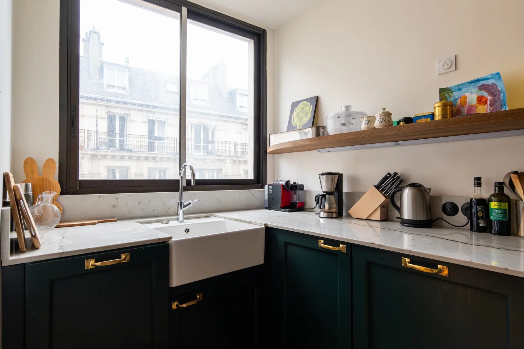 Una cocina luminosa con gabinetes oscuros y una ventana grande sobre el fregadero.
