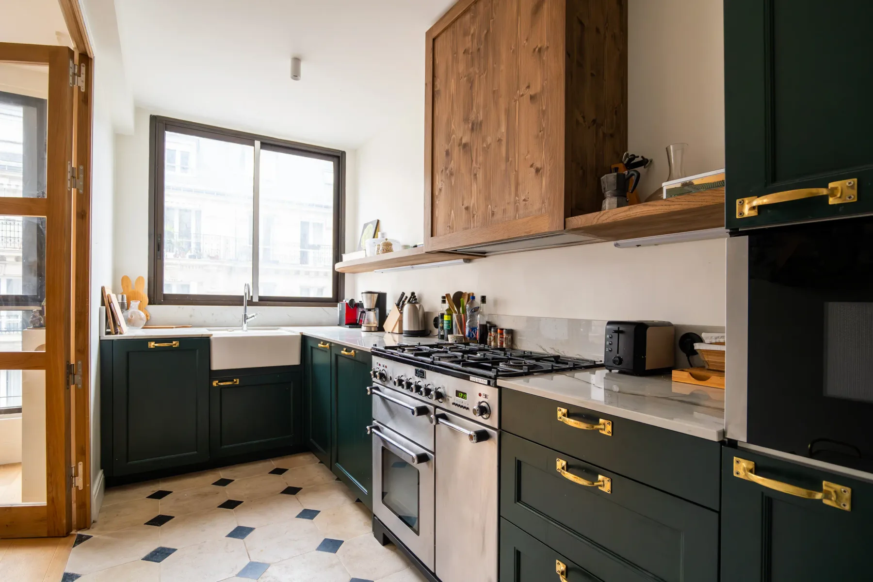 Cocina con gabinetes verde oscuro, encimeras claras y una cocina amplia.