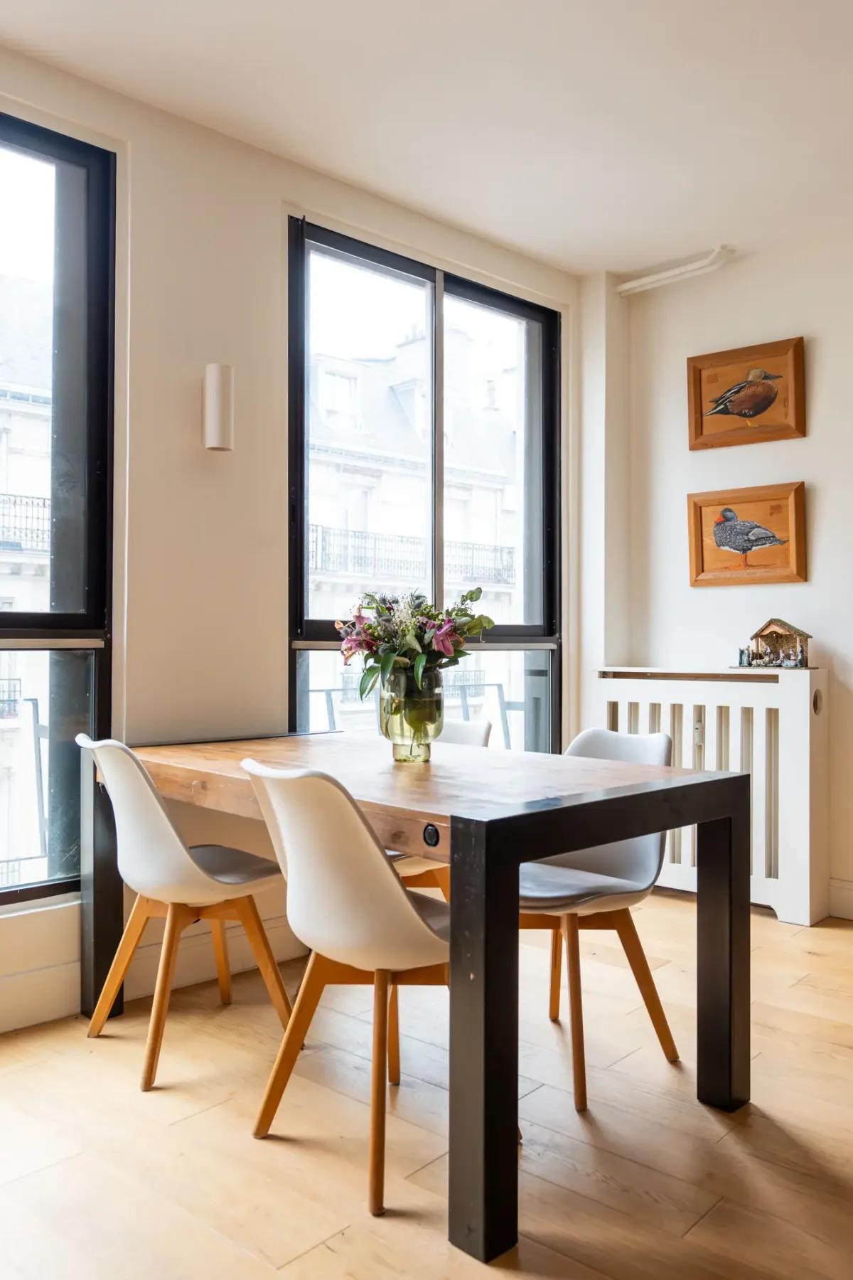 Comedor con una mesa de madera y asientos junto a grandes ventanas.