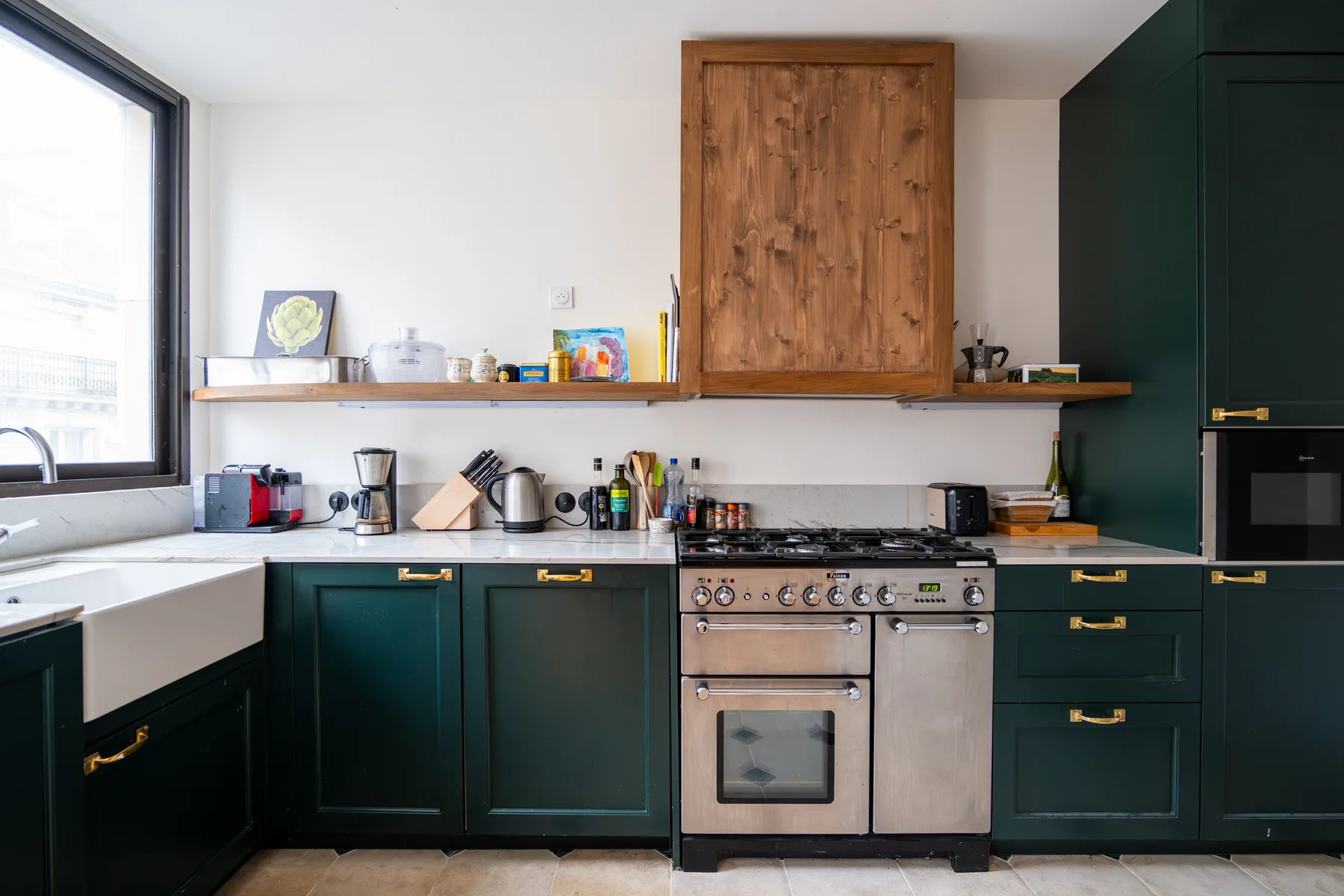 Una cocina moderna con gabinetes verde oscuro, un gabinete de madera y una estufa.