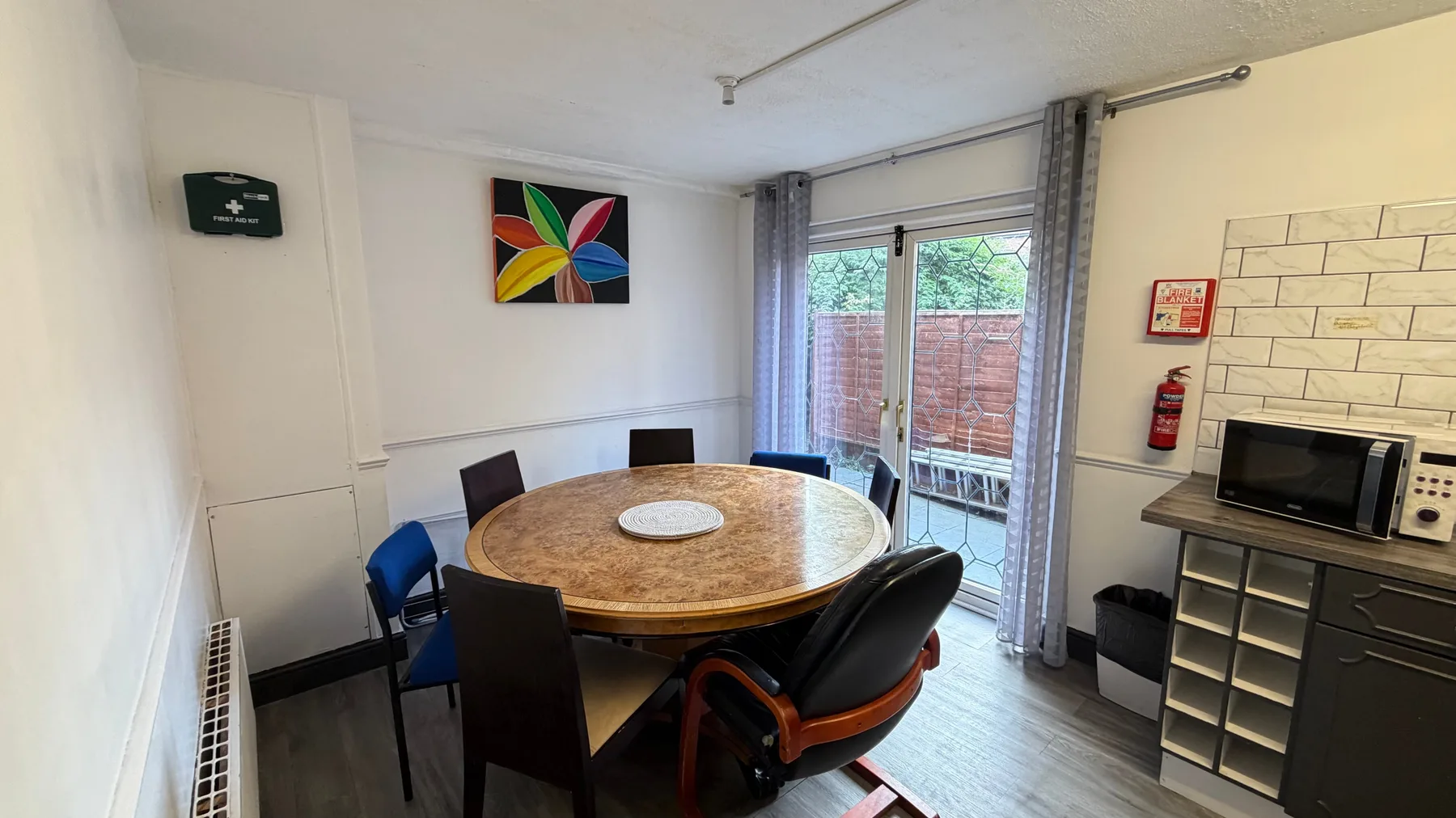 A dining area with a round table and sliding glass doors.