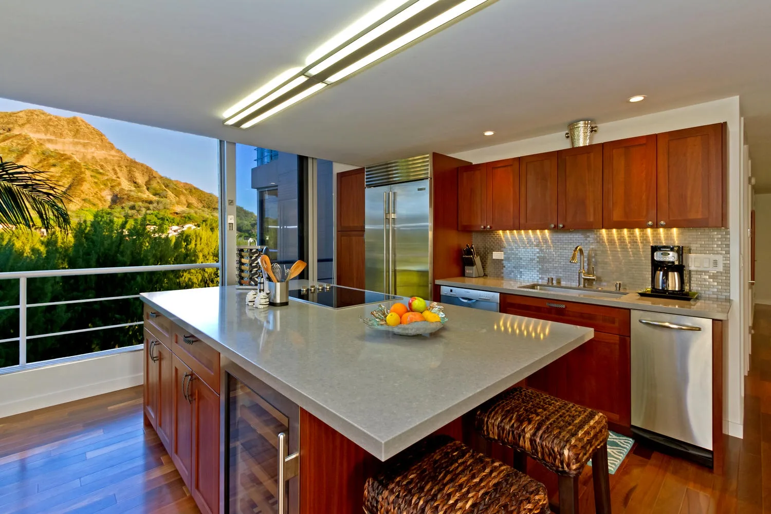 A modern kitchen with a large island and mountain views through wide windows.