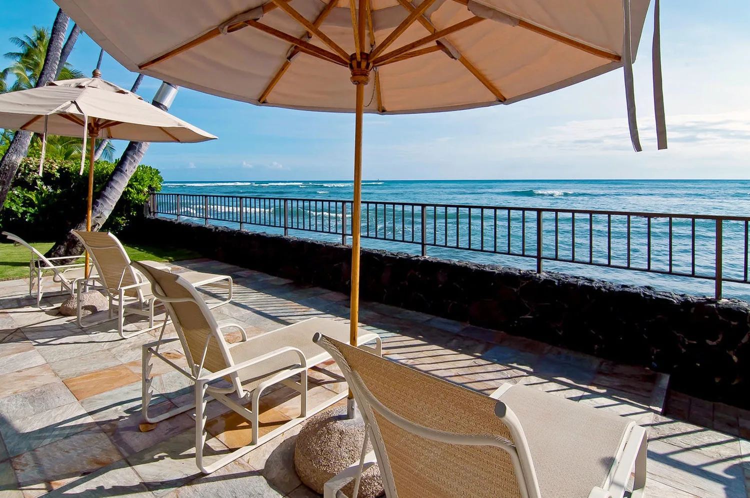 Un patio junto al mar con asientos a la sombra y vistas al océano.