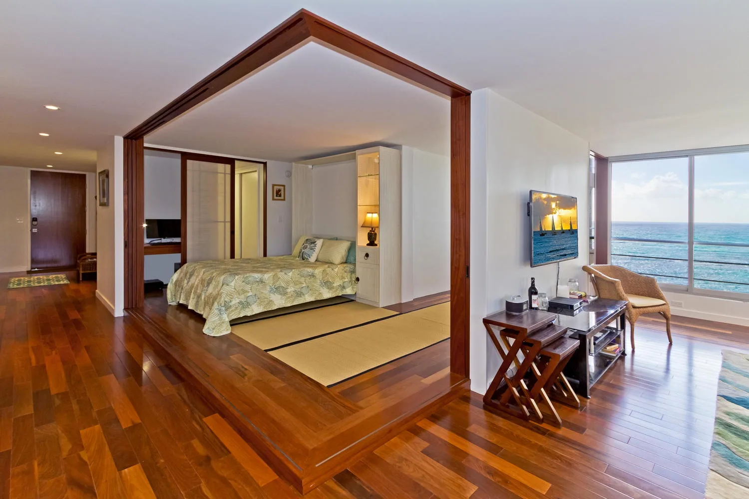 Un dormitorio se abre a una zona de estar junto a grandes ventanas con vistas al mar.