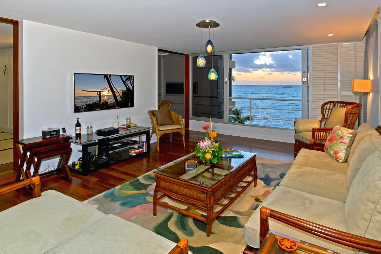 Una sala de estar con asientos alrededor de una mesa de centro y vistas al mar por puertas corredizas de vidrio.