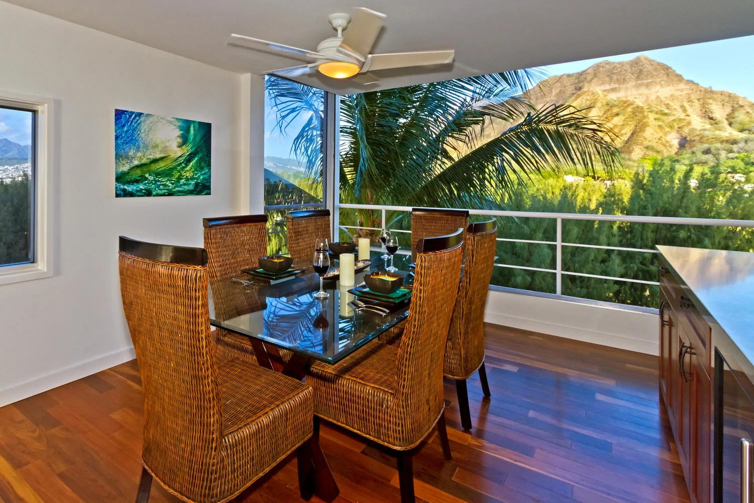 Comedor con asientos tejidos y una mesa de vidrio junto a una ventana panorámica.