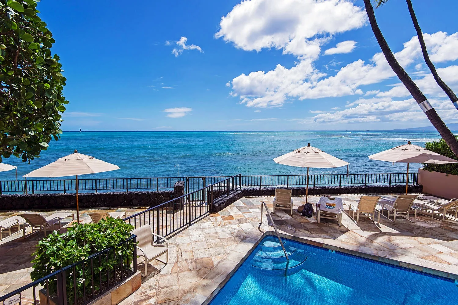 A poolside terrace overlooks the ocean, with umbrellas and outdoor seating.