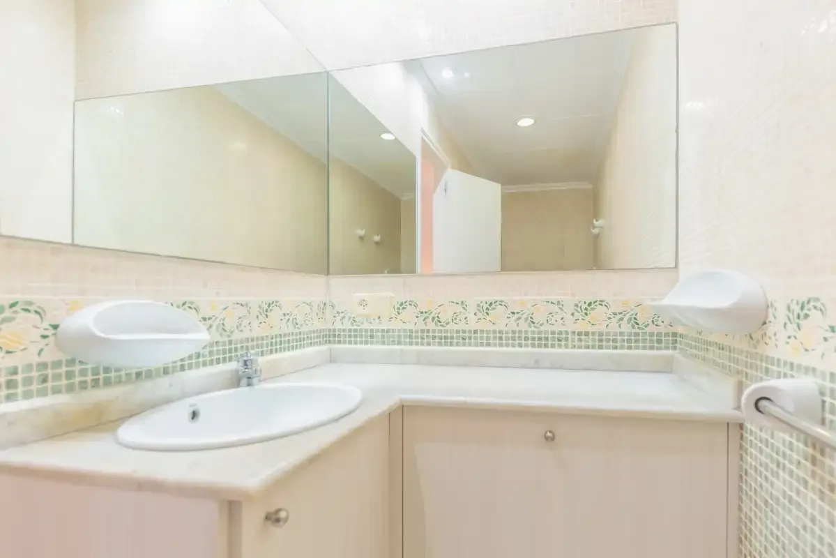 A bathroom vanity with a wide mirror and tiled backsplash.