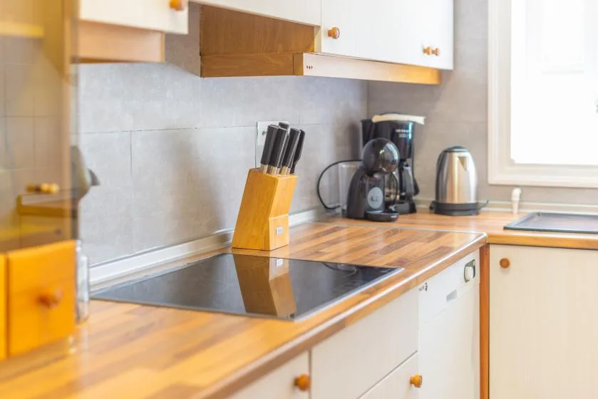 A kitchen counter with a cooktop, knife block, and small appliances.