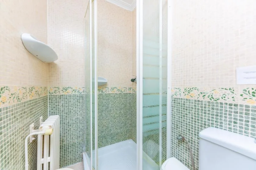 A tiled bathroom with a glass shower and toilet.