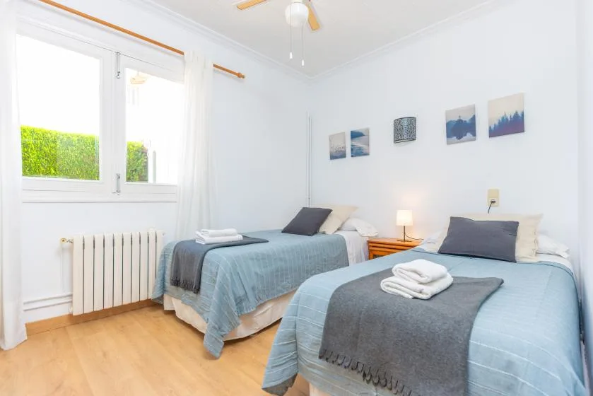 A bright bedroom with two beds dressed in blue bedding.