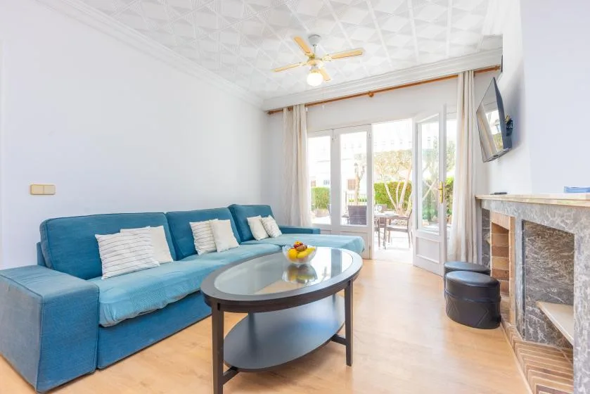 A bright living room with blue seating and glass doors opening onto a patio.