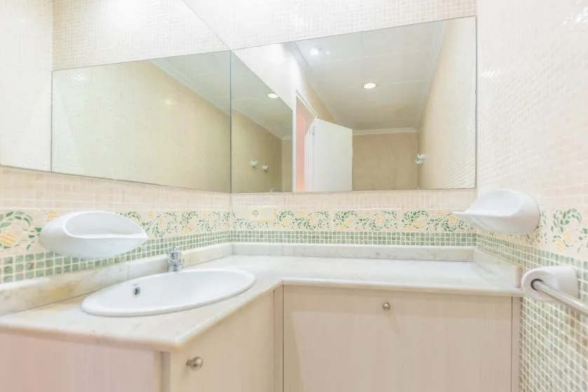A bathroom vanity with a wide mirror and a tiled backsplash.