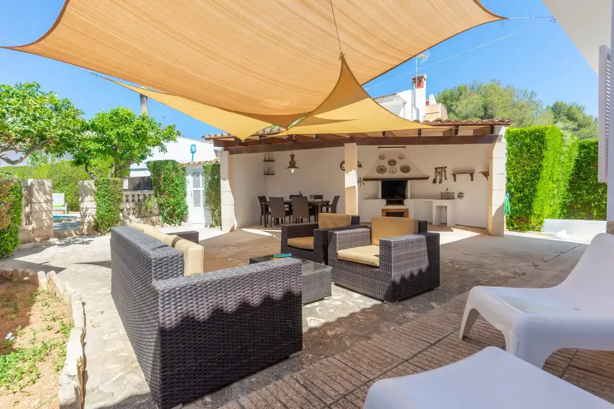 An outdoor dining and seating area sits beneath large shade sails.