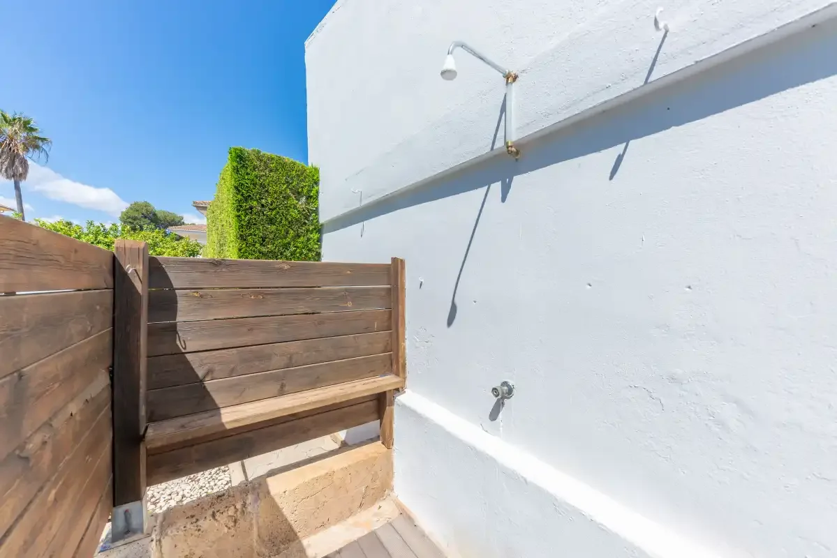 An outdoor shower beside a wooden privacy screen.