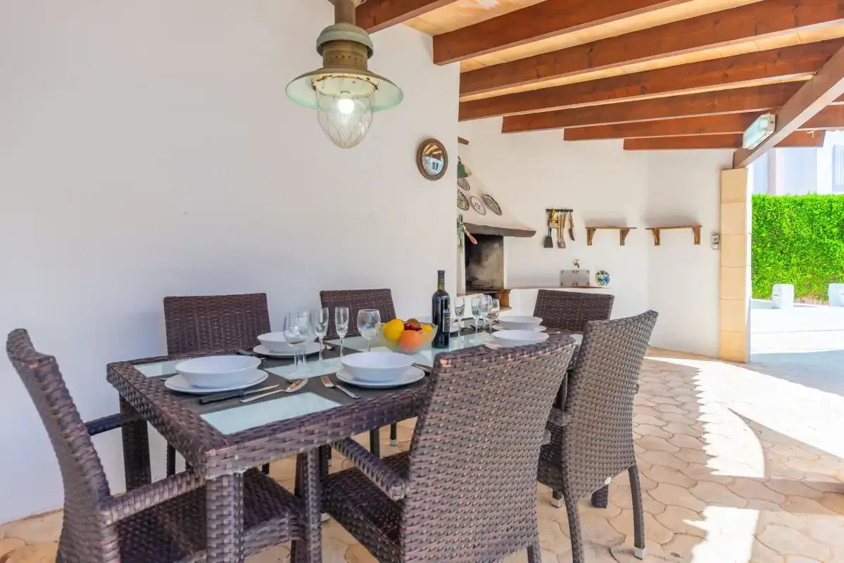 A dining area with a table and woven seating beneath exposed wooden beams.