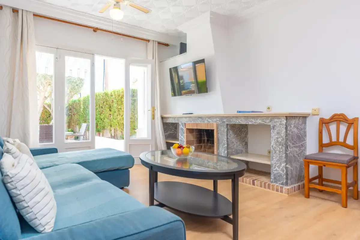 Living room with blue seating, a fireplace, and doors opening to a garden.