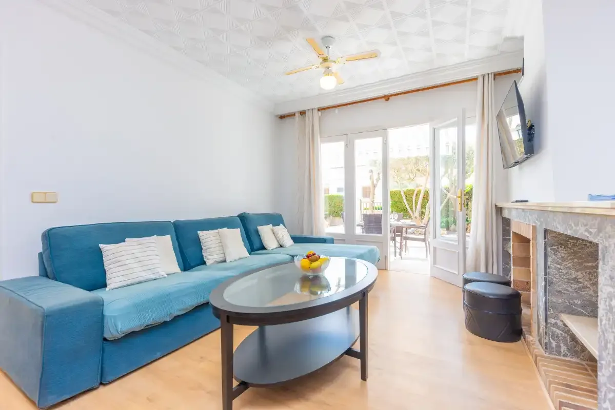 A bright living room with blue seating and glass doors opening onto a patio.