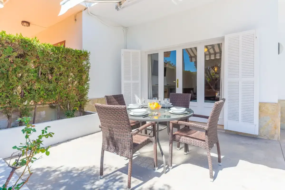 An outdoor dining area with a table and seating beside a white building.