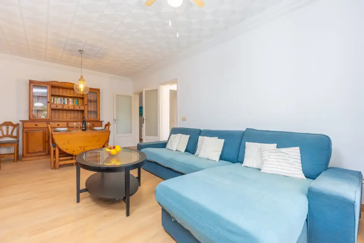 A living room with blue seating, a coffee table, and wooden cabinetry.