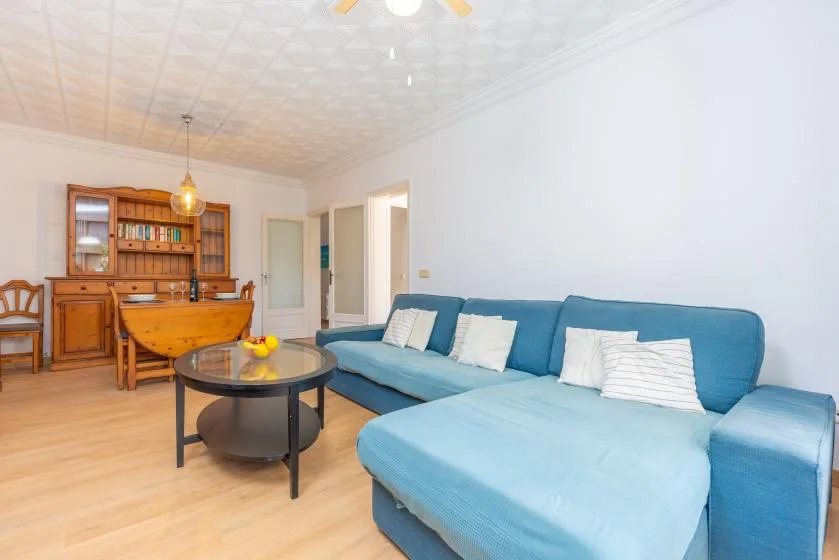 A living room with blue seating, a round coffee table, and a wooden cabinet.