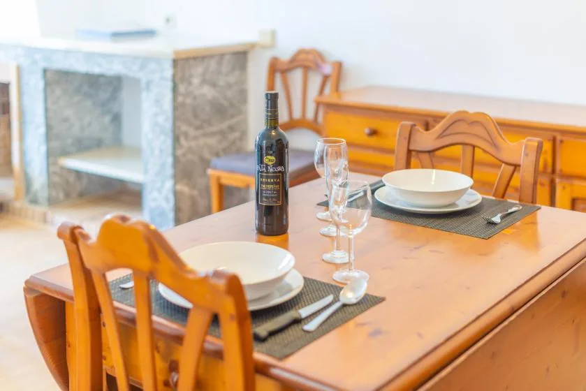 A dining area with a wooden table set with plates and glasses.