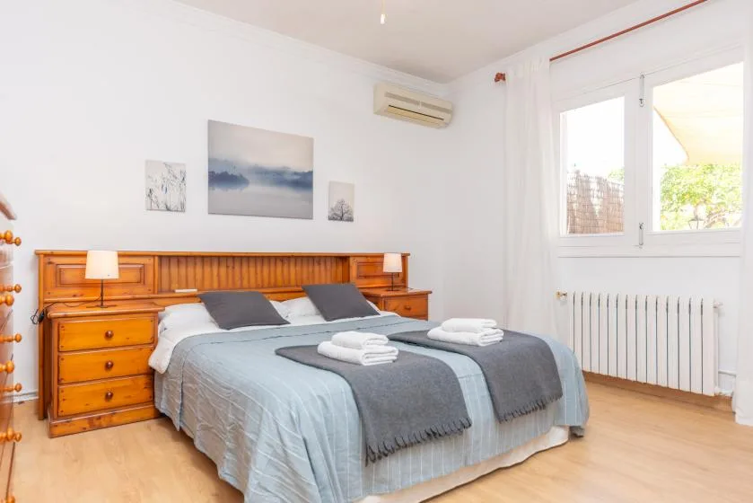A bedroom with a double bed, wooden headboard, and a bright window.