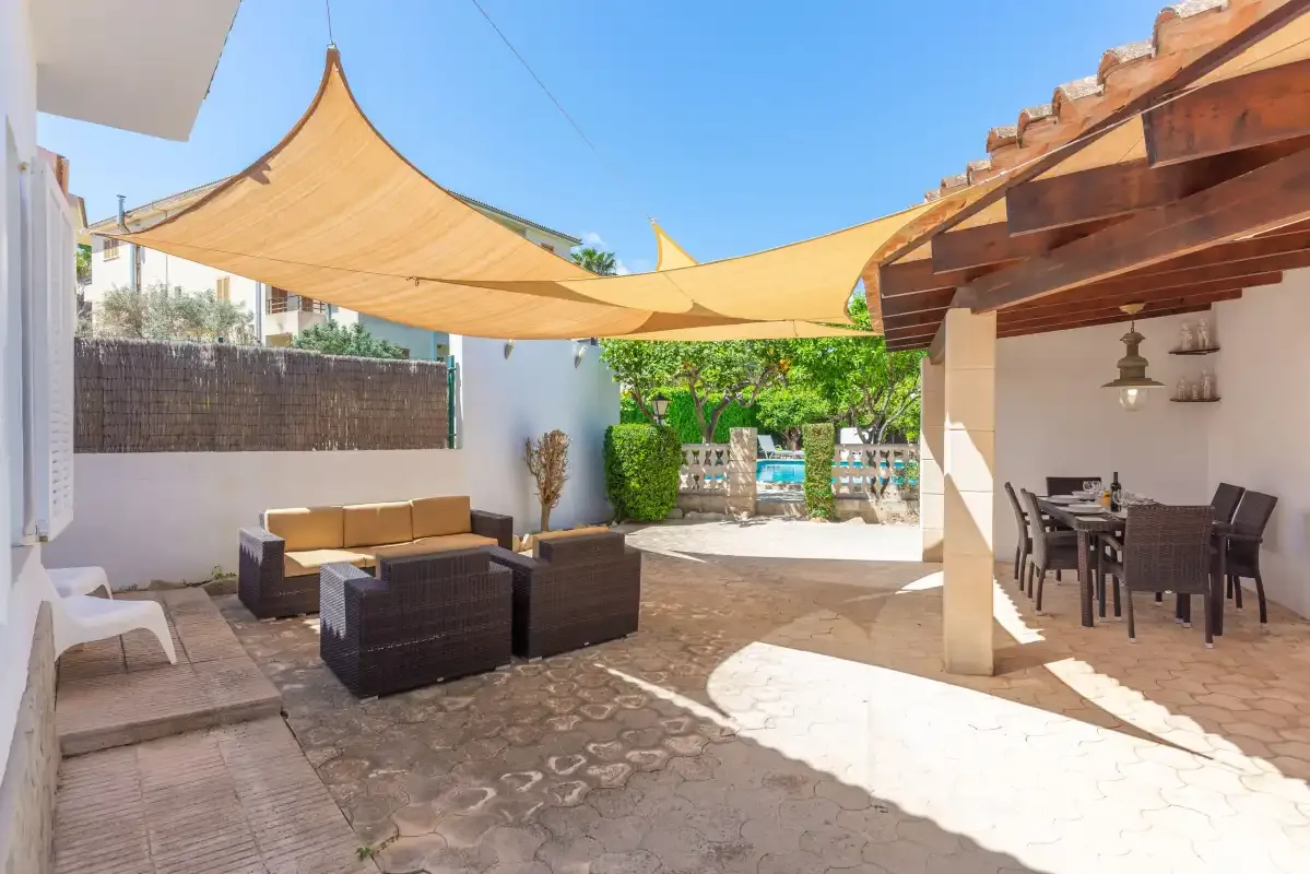 An outdoor patio has lounge seating and a shaded dining area.