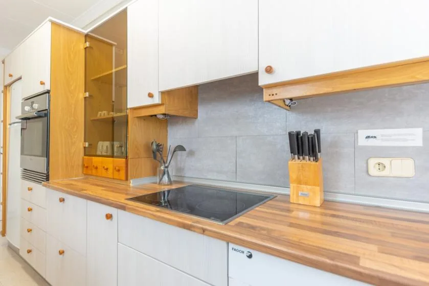 A kitchen counter with a built-in cooktop, cabinets, and cooking utensils.
