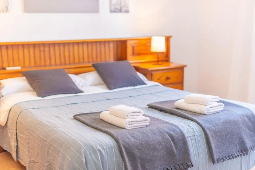 A bedroom with a neatly made bed and folded towels.