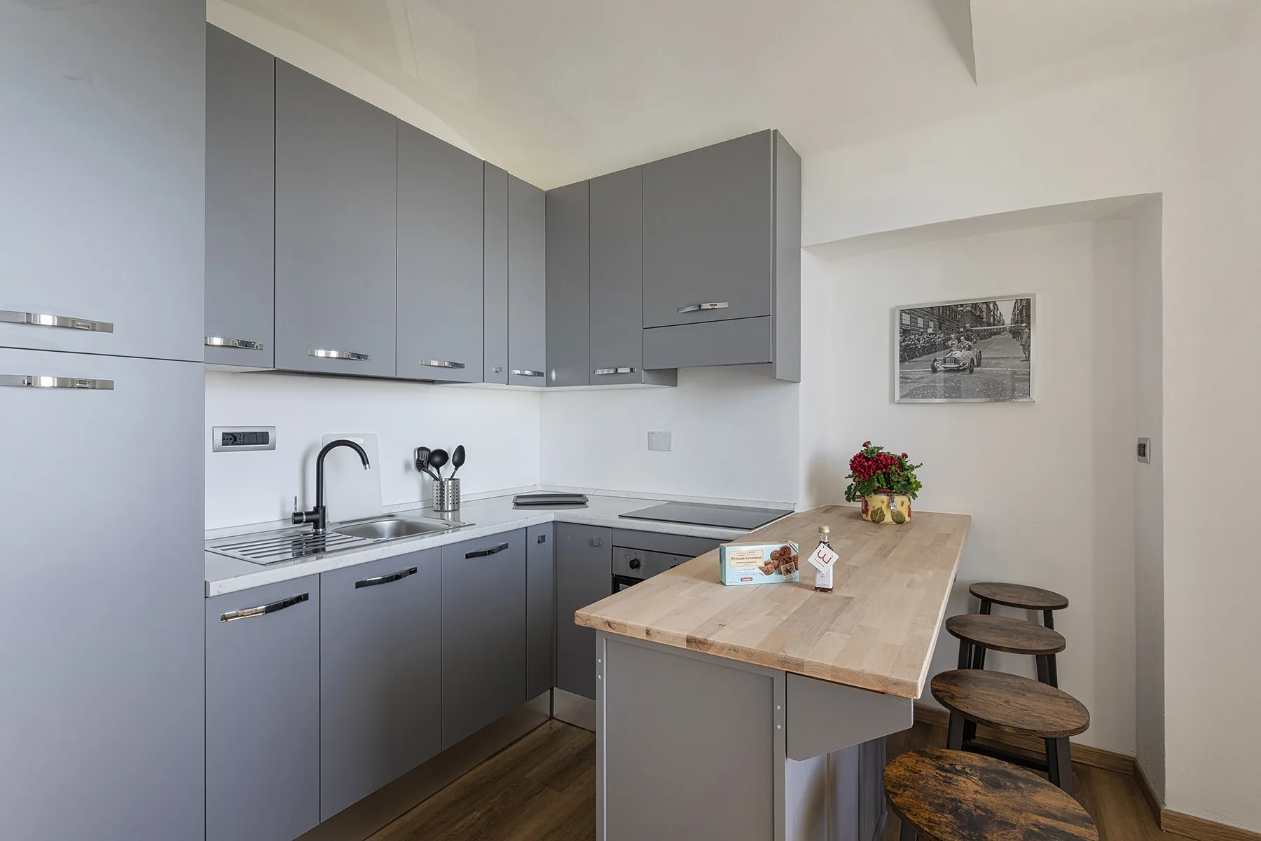 Una cocina moderna con gabinetes grises, una isla de madera y taburetes.