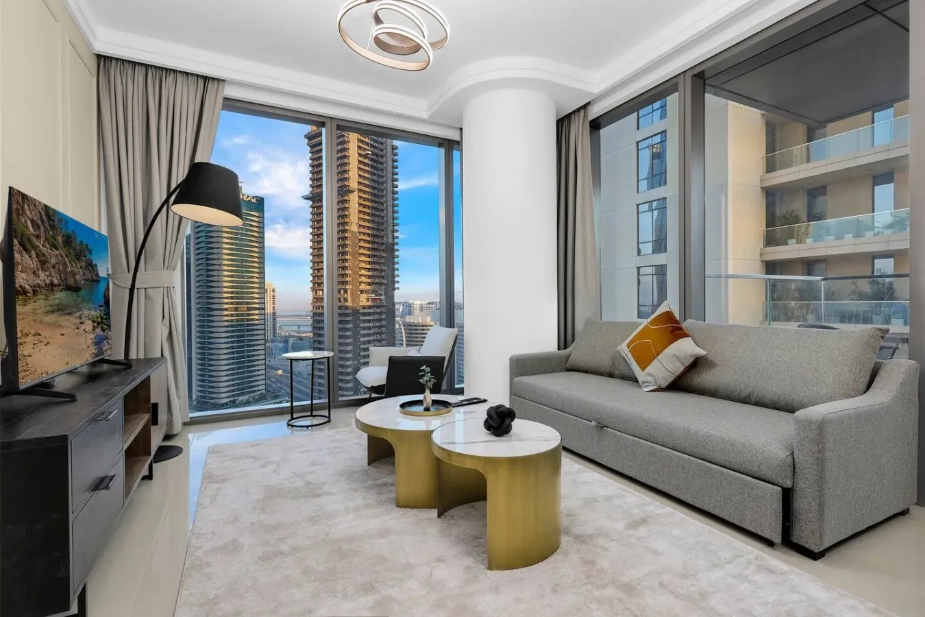 A living room with a gray sofa, coffee tables, and floor-to-ceiling windows.
