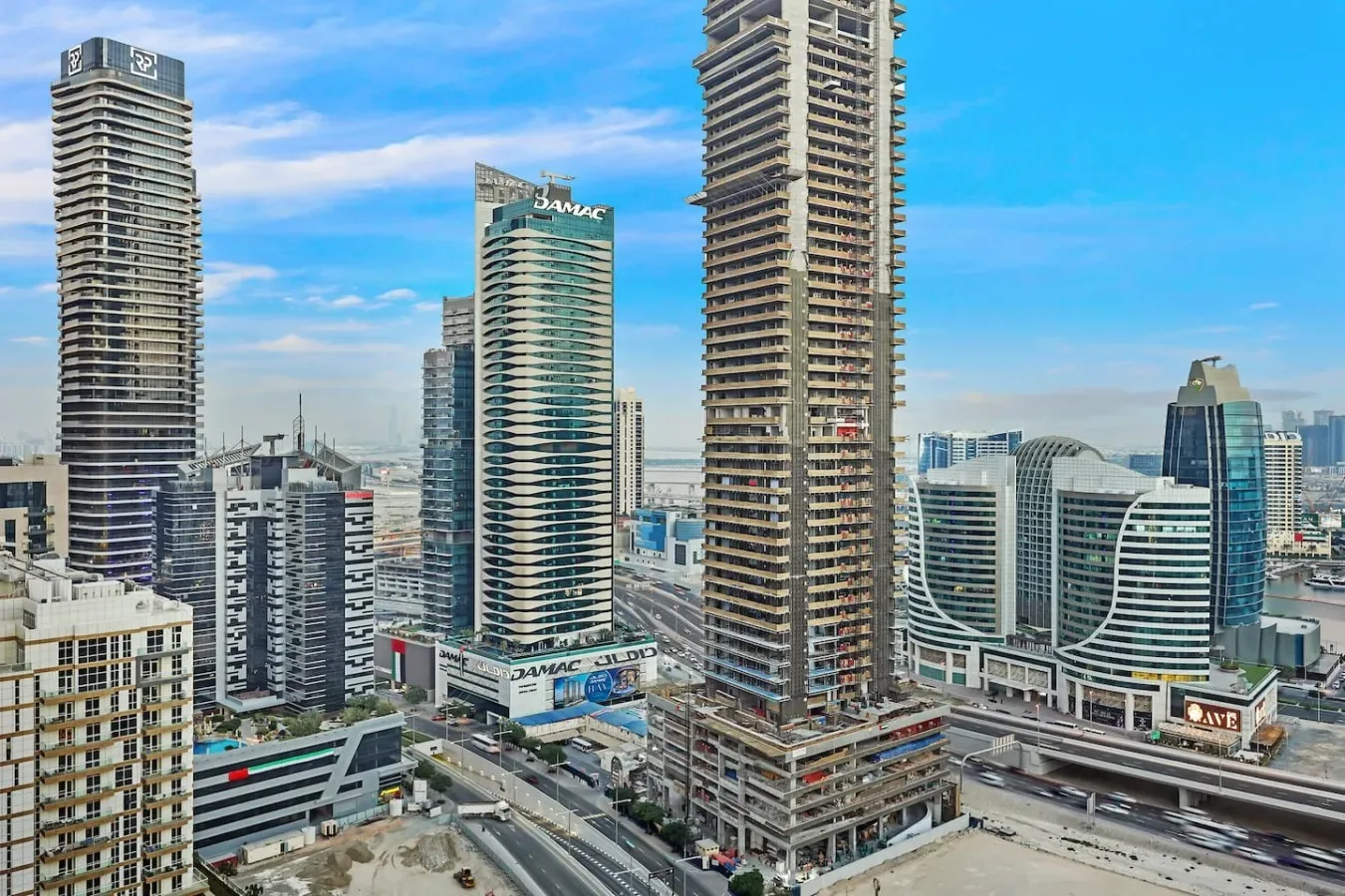 A city skyline of tall modern buildings beneath a clear blue sky.