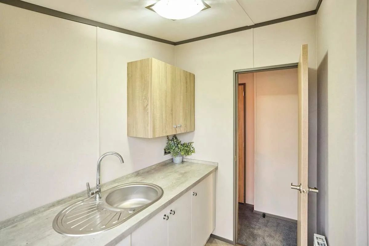 Una pequeña zona de cocina con fregadero, encimera y puerta abierta.