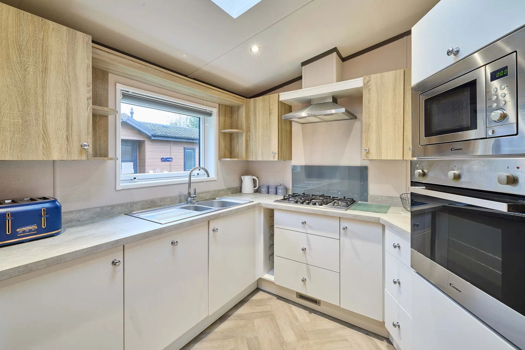 Una cocina luminosa con gabinetes de madera clara, una ventana y electrodomésticos integrados.
