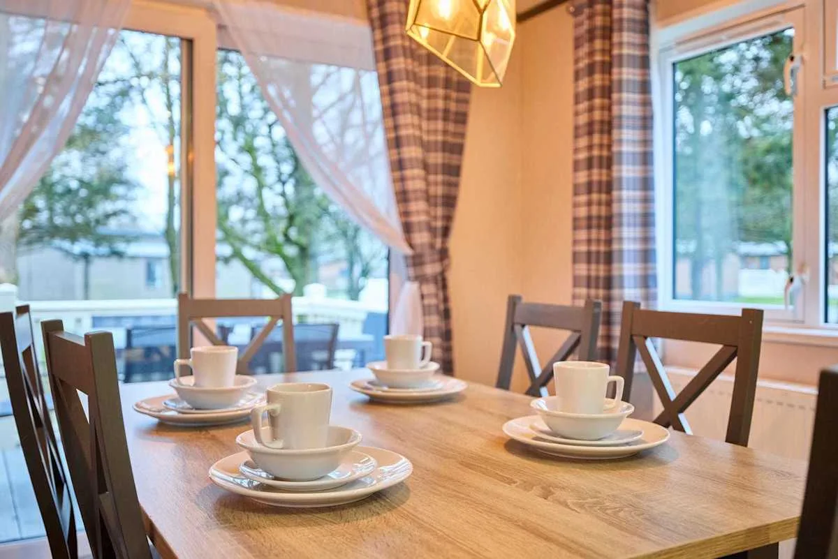 Comedor con una mesa de madera preparada con tazas y platillos.
