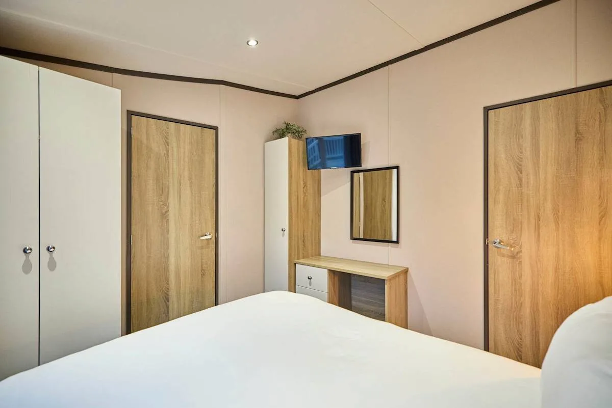 Un dormitorio con una cama, un armario y un pequeño tocador.