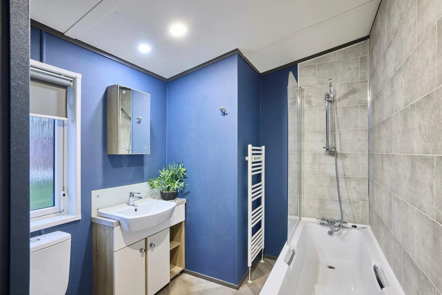 Un baño azul con lavabo, bañera y paredes revestidas de azulejos.