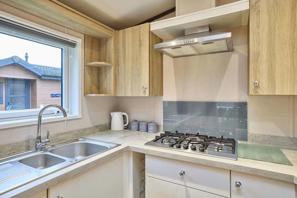 Una cocina con gabinetes de madera, un fregadero y una estufa de gas.