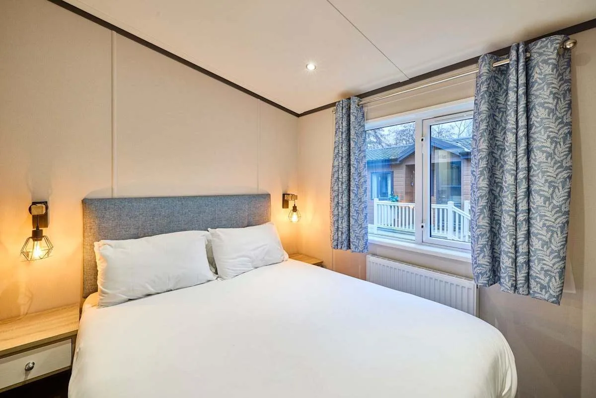 Un dormitorio con una cama y una ventana enmarcada por cortinas estampadas.