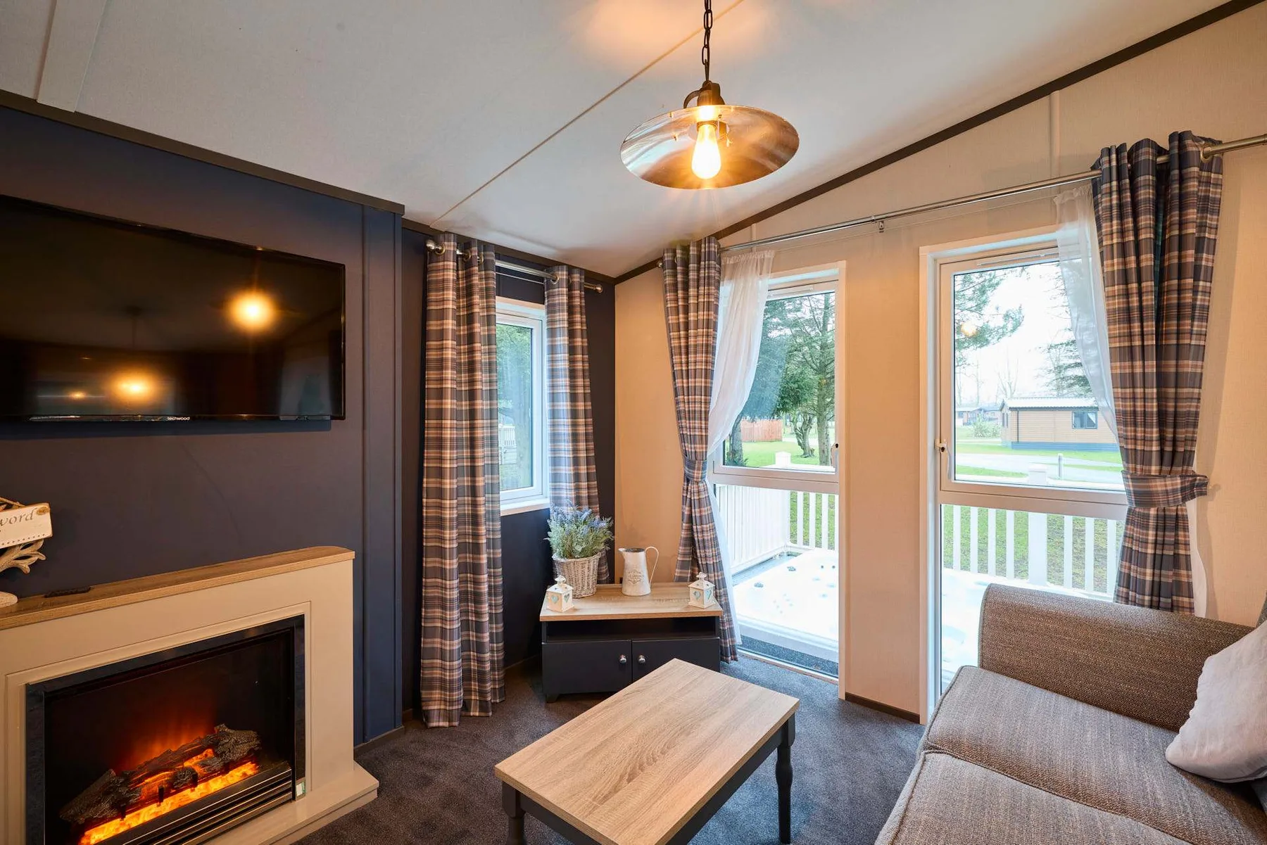 Una sala de estar con chimenea, televisor y ventanas con vistas a una terraza.