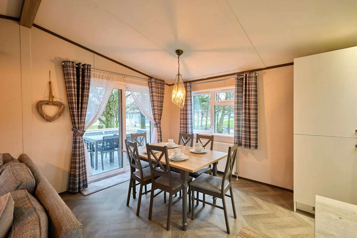 Comedor con una mesa de madera y ventanas que dan a un patio.