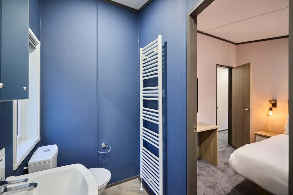 Un baño azul con lavabo y radiador toallero blanco.